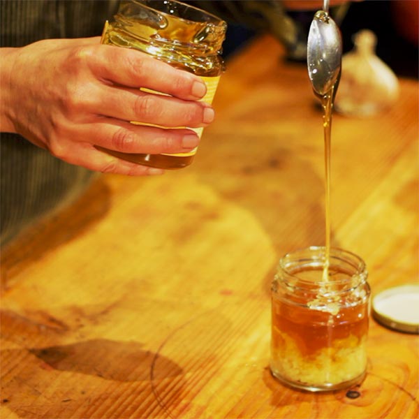Pouring honey into the jam-jar with the garlic